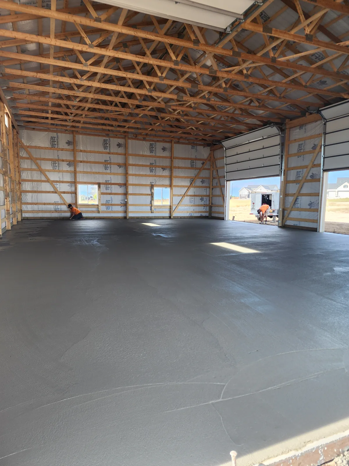 Freshly poured and troweled concrete slab inside a framed pole barn